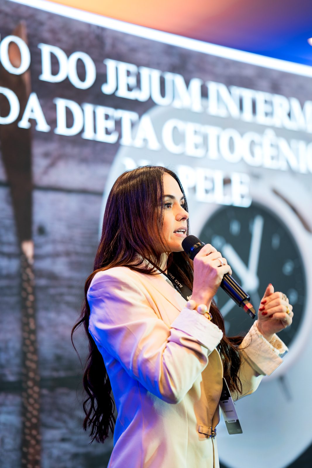Dra. Renata Nascimento palestrando com microfone em evento sobre metabolismo e emagrecimento feminino